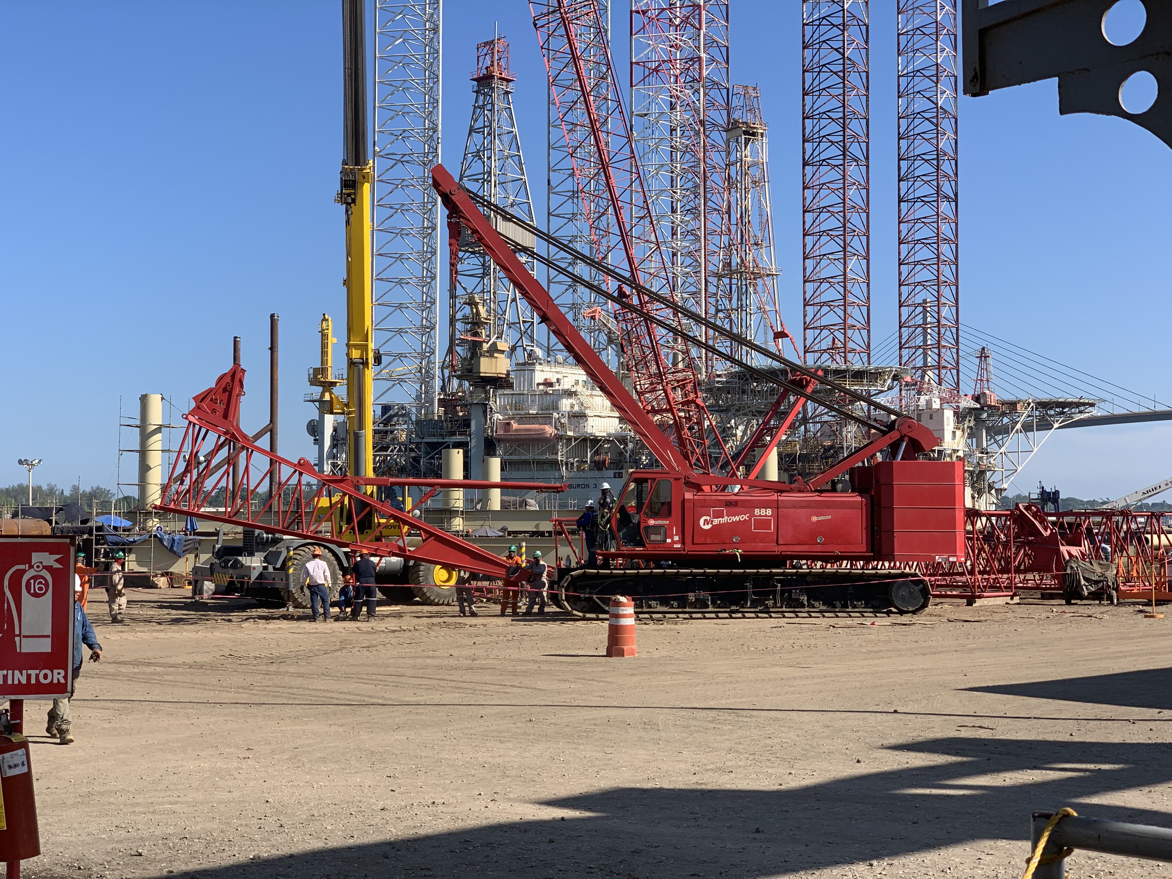 Grúa Manitowoc 888 en patio junto a plataformas marinas
